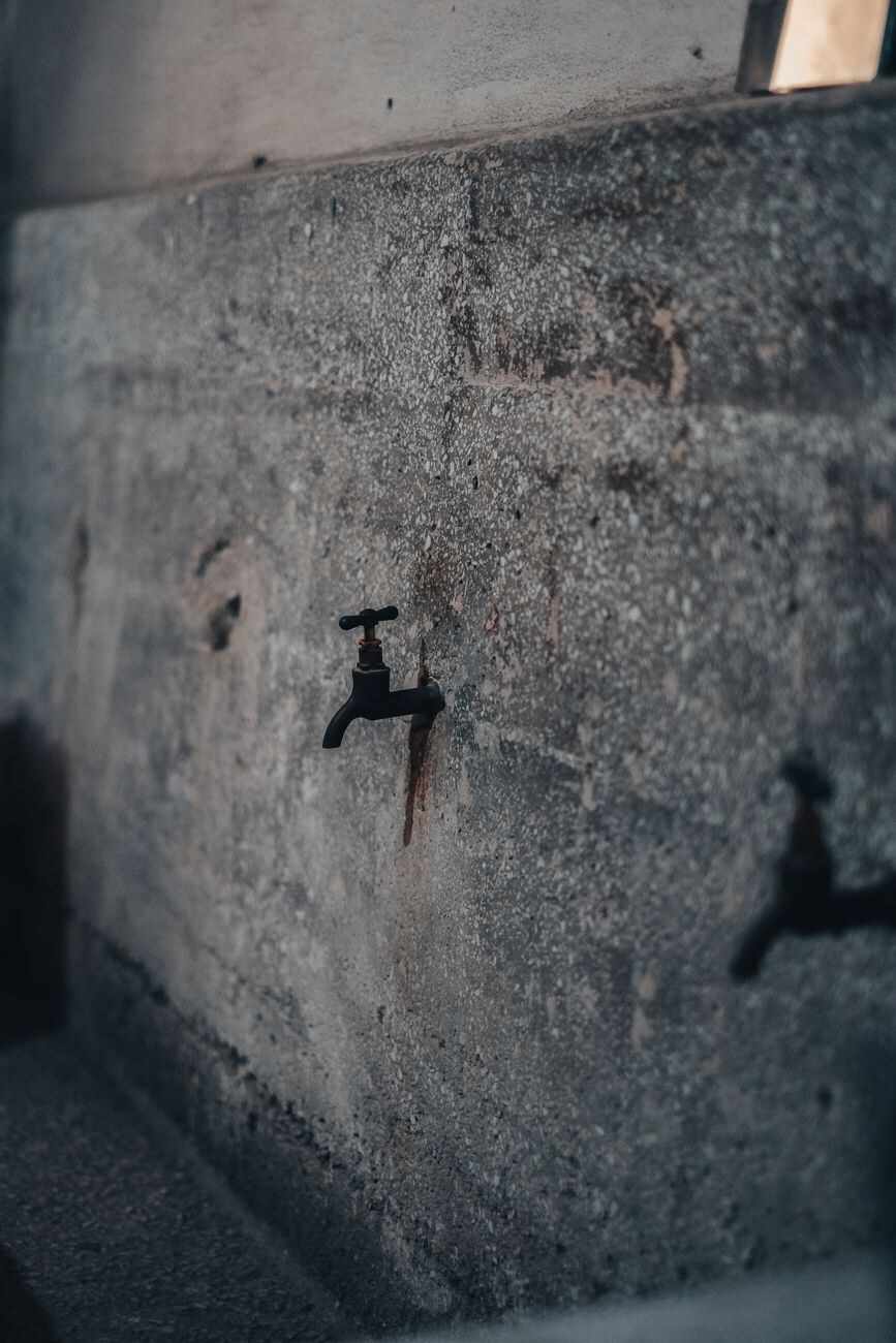 Beton duvarda aşağı doğru pas izi bırakmış tek vana