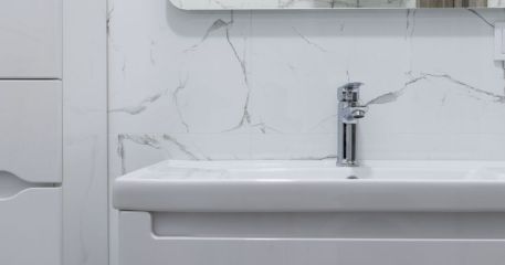 Mermer kaplı duvar önünde lavabo ve batarya