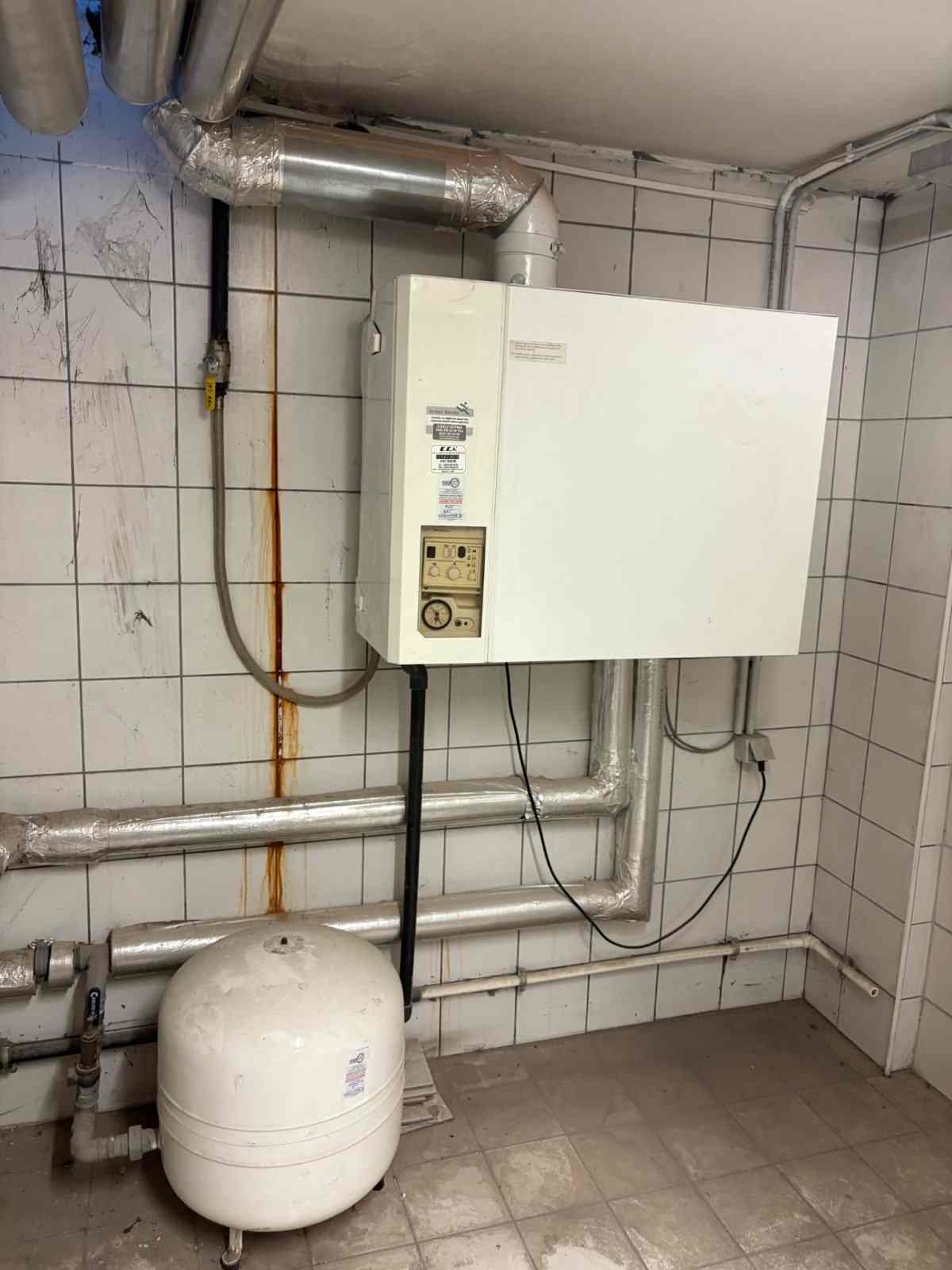 Duvar tipi kombi, altında genleşme tankı ve sarı gaz hattı