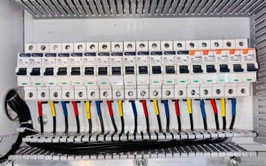 Elektrik panosunda sıralanmış otomatik sigortalar ve besleme kabloları