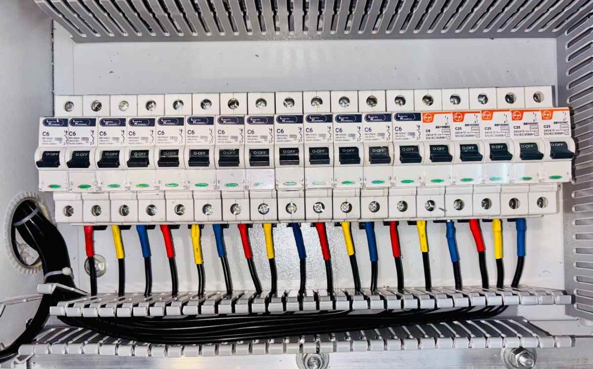 Elektrik panosunda sıralanmış otomatik sigortalar ve besleme kabloları