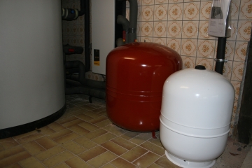Tesisat odasında yan yana duran kırmızı ve beyaz genleşme tankları