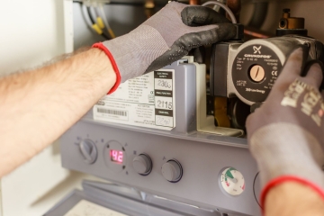 Kombi servisi teknisyeni açık kombide sirkülasyon pompasını kontrol ediyor
