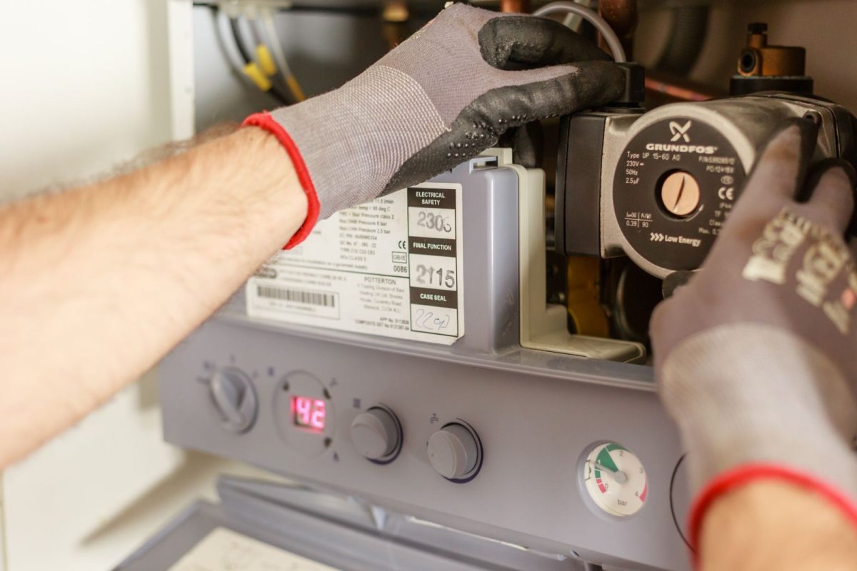 Kombi servisi teknisyeni açık kombide sirkülasyon pompasını kontrol ediyor