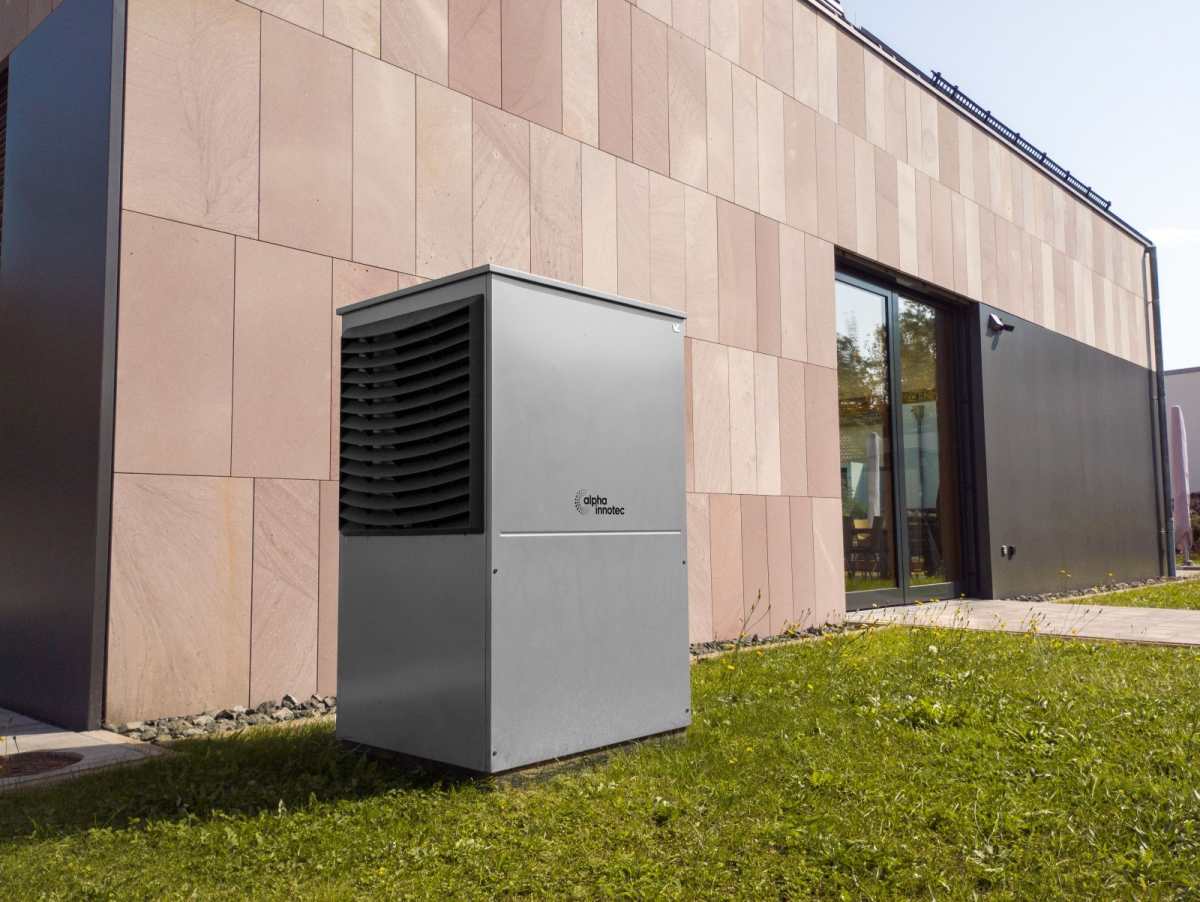 Müstakil evin cephesi yanında çim üzerine oturtulmuş ısı pompası dış ünitesi