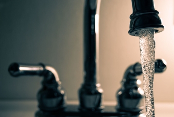 Açık bir lavabo bataryasından akan su — sıcak suyun musluğa gecikmeli gelmesi